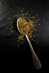 Top view of a spoon with oregano powder isolated on black