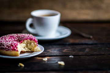 Bite a Pink donut with white sprinkle