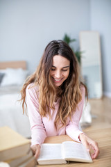Happy smiling student girl reading book at home.