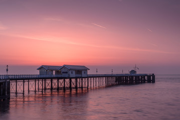 Obraz premium Penarth Pier, on the south Wales coast, near Cardiff, at sunrise. The sky is red and orange, and the sea is smooth