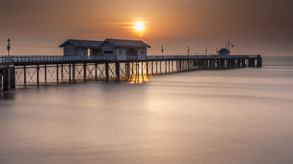 Penarth Pier, on the south Wales coast, near Cardiff, at sunrise. The sky is  orange, and the sea is smooth