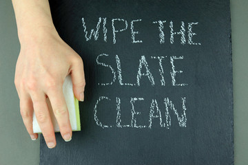 A Hand Holding A Cleaning Sponge Ready To Wipe The Slate Clean