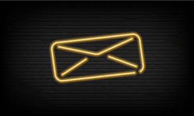 Fototapeta premium Neon icon of closed yellow post envelope on background of brick wall on roadside. Bright electric advertise