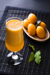 glass of orange juice and oranges on wooden table