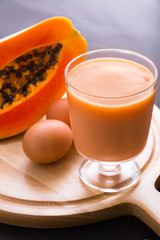 glass of papaya juice and egg on wooden table