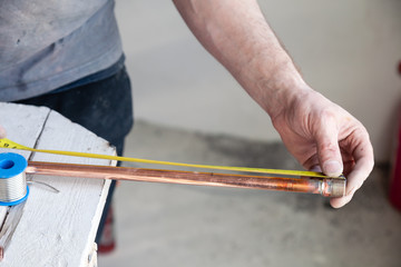 Closeup worker plumber master measures copper pipes with roulette tape, cut pipe with cutter....