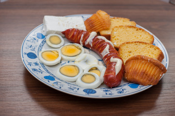 Tasty grilled sausages with cheese and eggs on plate on wooden table