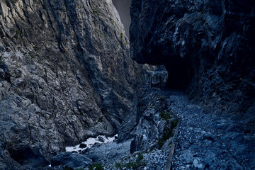 Old narrow mountain path in a canyon, railing on the side, black 