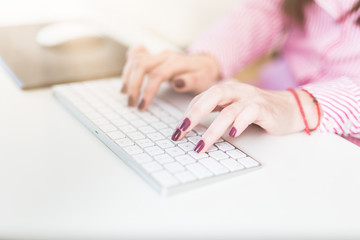 Woman fingers typing on desktop computer keyboard.