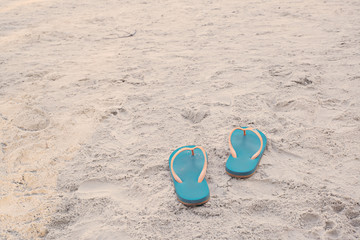  Summer vacation concept. Flip flops on a sandy ocean beach