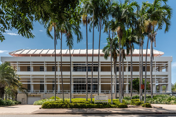 Darwin Australia - February 22, 2019: Supreme Court of the Northern Territory building behind palm trees is modern construction under blue sky.