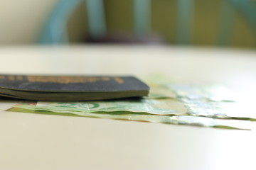 Canadian passport laying on top of twenty dollar bills. Concept of immigrating or emigrating, or travelling with a canadian passport