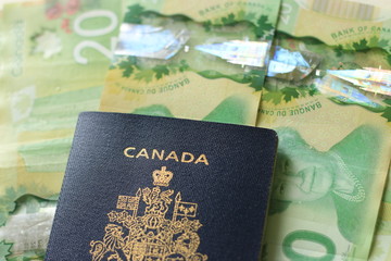Canadian passport laying on top of twenty dollar bills. Concept of immigrating or emigrating, or...