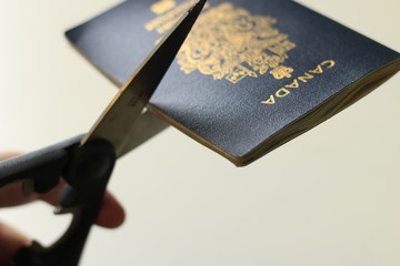 Cutting a canadian passport. Concept of renouncing citizenship or leaving the country....
