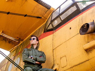 Fototapeta na wymiar A handsome young pilot sitting on the wing of a plane