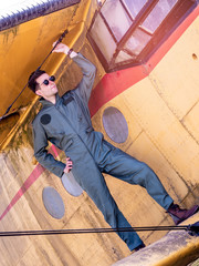 Fototapeta na wymiar A handsome young pilot standing on the wing of a plane