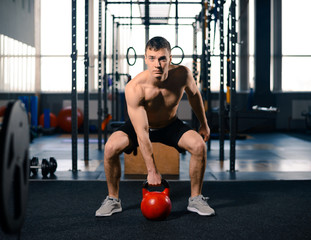 Portrait of Young Sportsman Lifting Heavy Dumbbells in Gym. Fitness and Healthy Lifestyle Concept. Dramatic Lighting