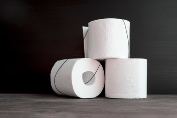 White toilet paper rolls on wooden table. Black background. Selective fcus. Copy space.