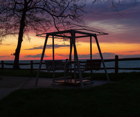 Park swinging bench with colorful dramatic sky 