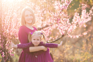 Happy mother holding baby girl playing outdoors over nature. Summer time. Motherhood.