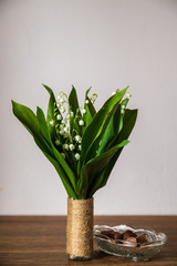 Bouquet of Lily of the valley or convallaria majalis in a vase on wooden table