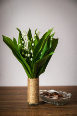 Bouquet of Lily of the valley or convallaria majalis in a vase on wooden table