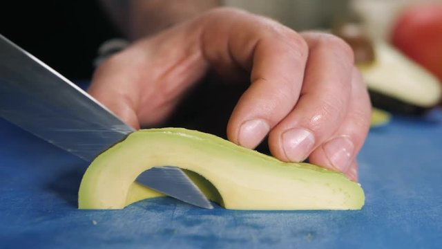 Close up of chef male hands cooking with avocado at table slice knife cut macro