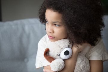 Unfortunate stray biracial kid girl embrace stuffed toy looking aside