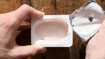 Opening jar of yogurt. Man opens plastic jar of fruit yogurt - Powered by Adobe