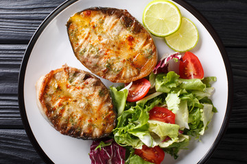 fried sturgeon steaks served with fresh vegetable salad close-up on a plate. horizontal top view