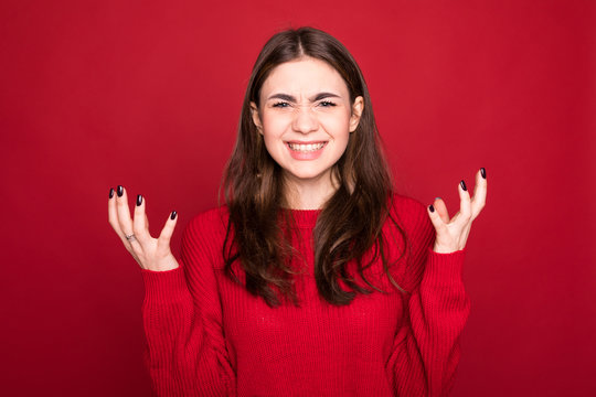 Close up isolated portrait of young annoyed angry woman holding hands in furious gesture on red background. Negative human emotions, face expressions.