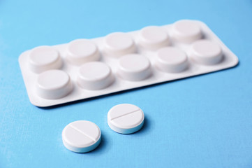 White round pills closeup on blue background