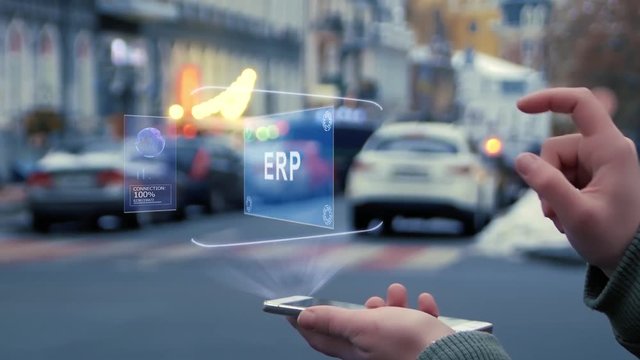 Female hands on the street interact with a HUD hologram with text ERP. Woman uses the holographic technology of the future in the smartphone screen on the background of the evening city
