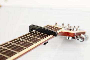 Acoustic guitar neck with capo on a white background