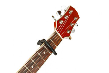 Acoustic guitar neck with capo on a white background