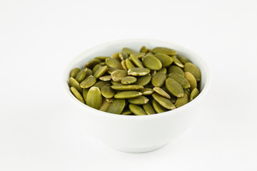 Peeled green pumpkin seeds in a white bowl
