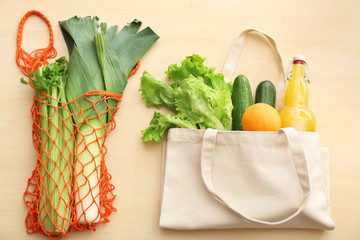Eco bags with products on wooden background. Zero waste concept