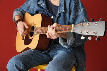 Handsome young man playing guitar on color background