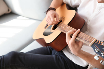 Fototapeta premium Handsome young man playing guitar at home