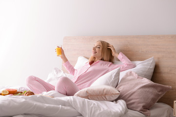 Beautiful young woman having breakfast in bed