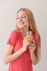 Beautiful young woman with fresh juice on light background