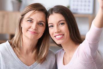 Portrait of happy mother and daughter taking selfie at home