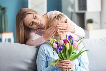 Fototapeta na wymiar Daughter greeting her mother with flowers at home