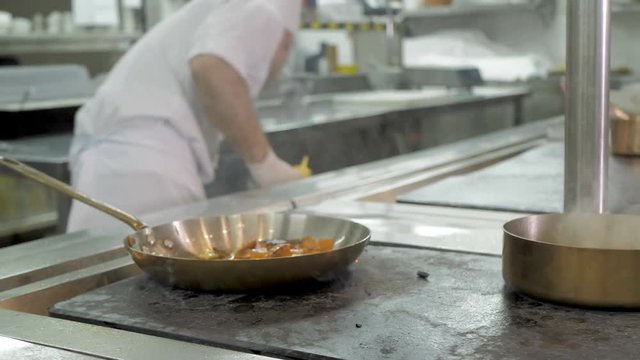 Chef cooking vegetables in pan in the kitchen of the restaurant or hotel