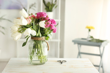Fototapeta na wymiar Vase with bouquet of flowers on table