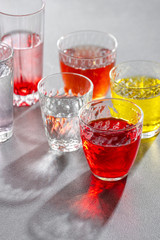 Glass cups with colorful cold drinks on a gray stone table. Shooting with hard light.