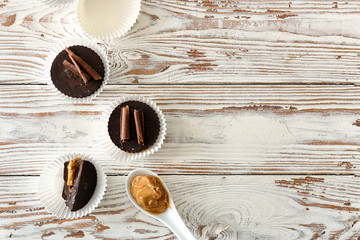Tasty chocolate peanut butter cups on white wooden table