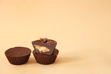 Tasty chocolate peanut butter cups on color background
