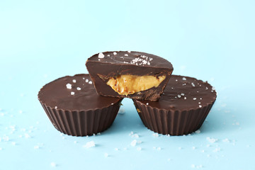 Tasty chocolate peanut butter cups on color background