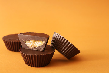 Tasty chocolate peanut butter cups on color background